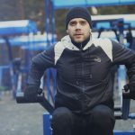 Tilt up of Young athlete man doing exercise at outdoor gym in winter park outdoors