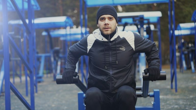 Tilt up of Young athlete man doing exercise at outdoor gym in winter park outdoors