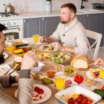 Cozy indoor gathering of friends at a table set with diverse dishes and orange juice.